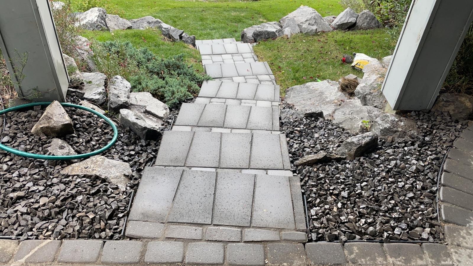 Boulder retaining wall with integrated stone steps in a Calgary yard by Sungreen.