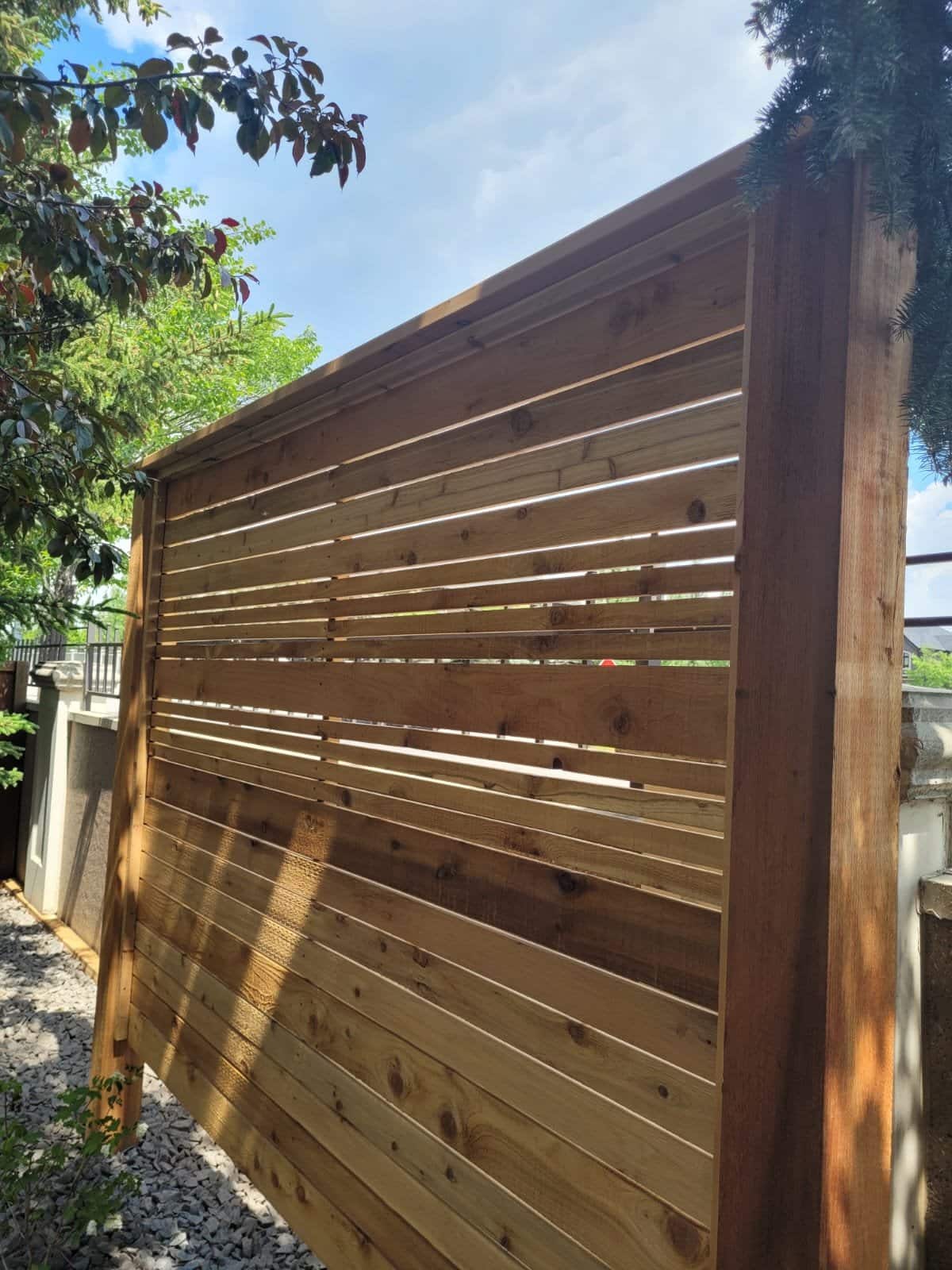 Horizontal cedar slat privacy fence under a blue sky at a Calgary home by Sungreen.