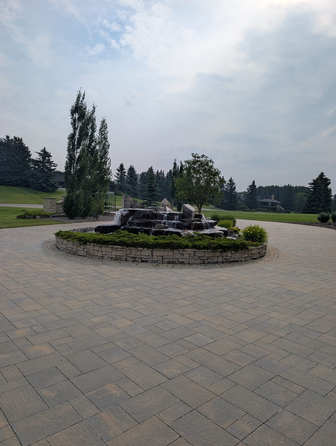 Complete Sungreen landscape build in the Calgary area: paver courtyard, planting and water feature.