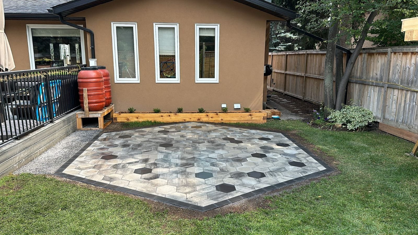 Circular paving-stone patio with a built-in firepit in a Calgary backyard by Sungreen.