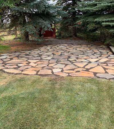Natural flagstone patio with a stone border in a Calgary garden by Sungreen.