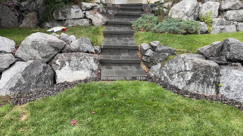 Circular flagstone path winding through a Calgary garden bed by Sungreen.