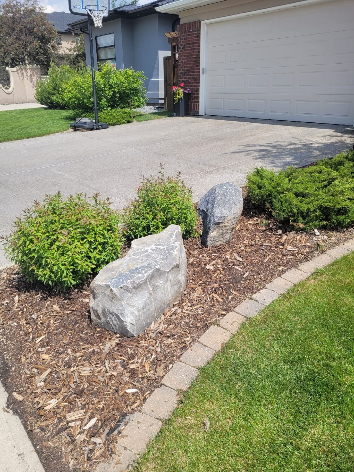 Front-yard landscape design in Calgary with boulder accents and layered shrub beds by Sungreen.