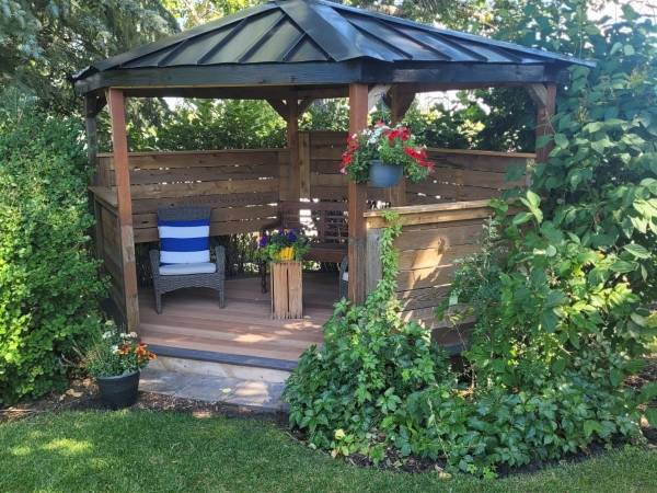 Hardtop gazebo with seating and hanging baskets in a Calgary garden by Sungreen.