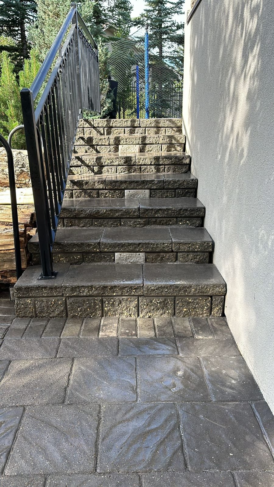 Paving-stone steps with a black metal railing leading up from a Calgary patio by Sungreen.