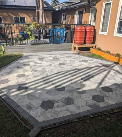 Two-tone hexagonal paving-stone patio set into a Calgary backyard lawn by Sungreen.